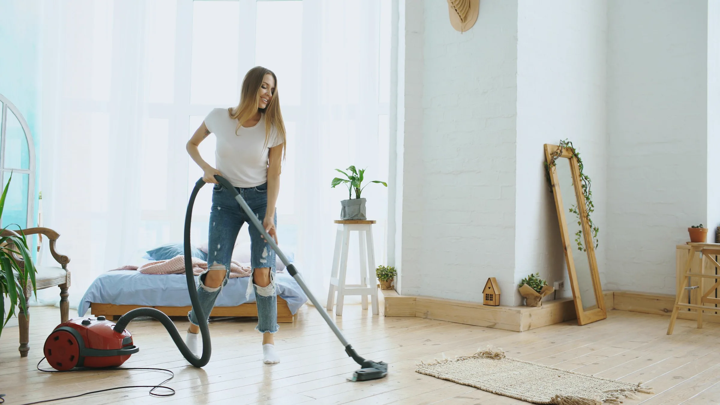 A person vacuuming the floor in a bright home