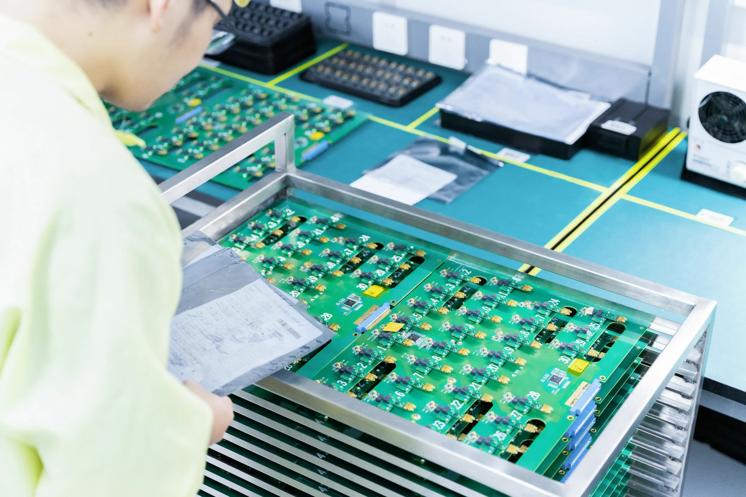 An electronics worker inspecting circuit boards at a production workstation