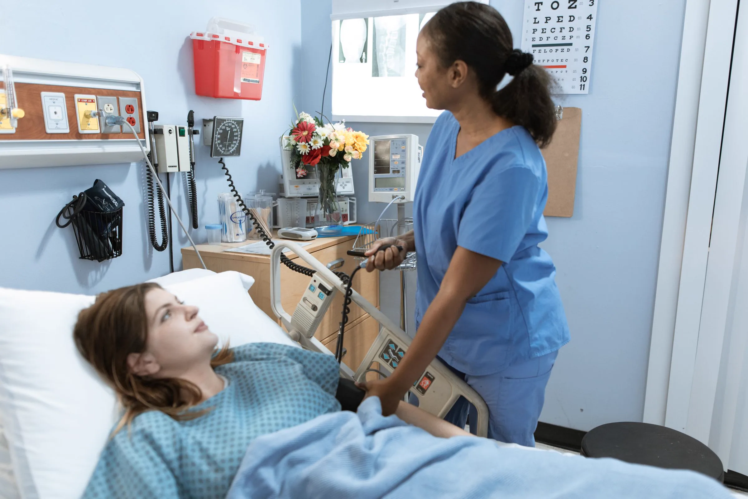 A public service environment with a nurse, patient, hospital bed, and medical equipment